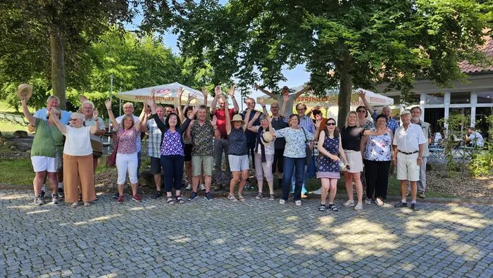 Eine Gruppe von Menschen steht vor Bäumen und lacht.