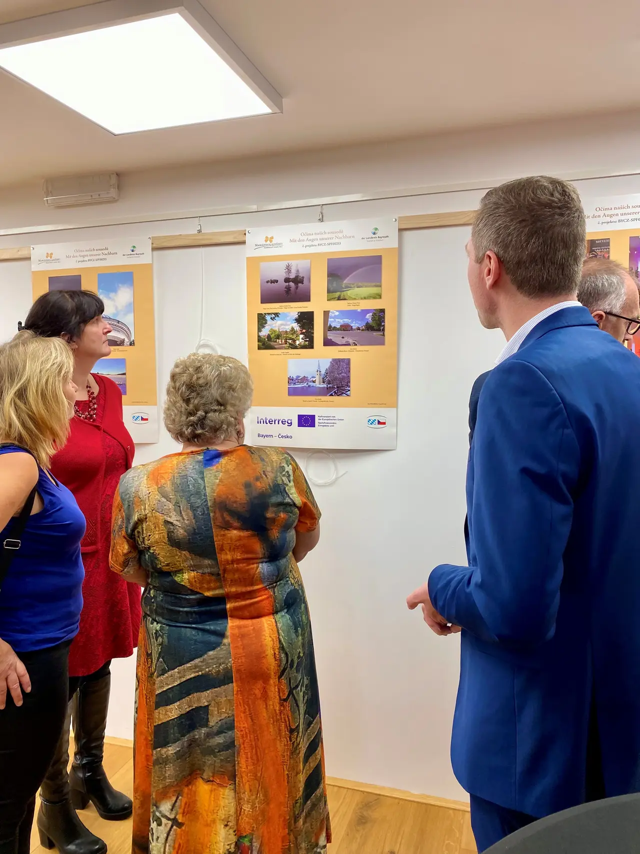 Eine Gruppe schaut sich ein Ausstellungsplakat mit Fotografien an.