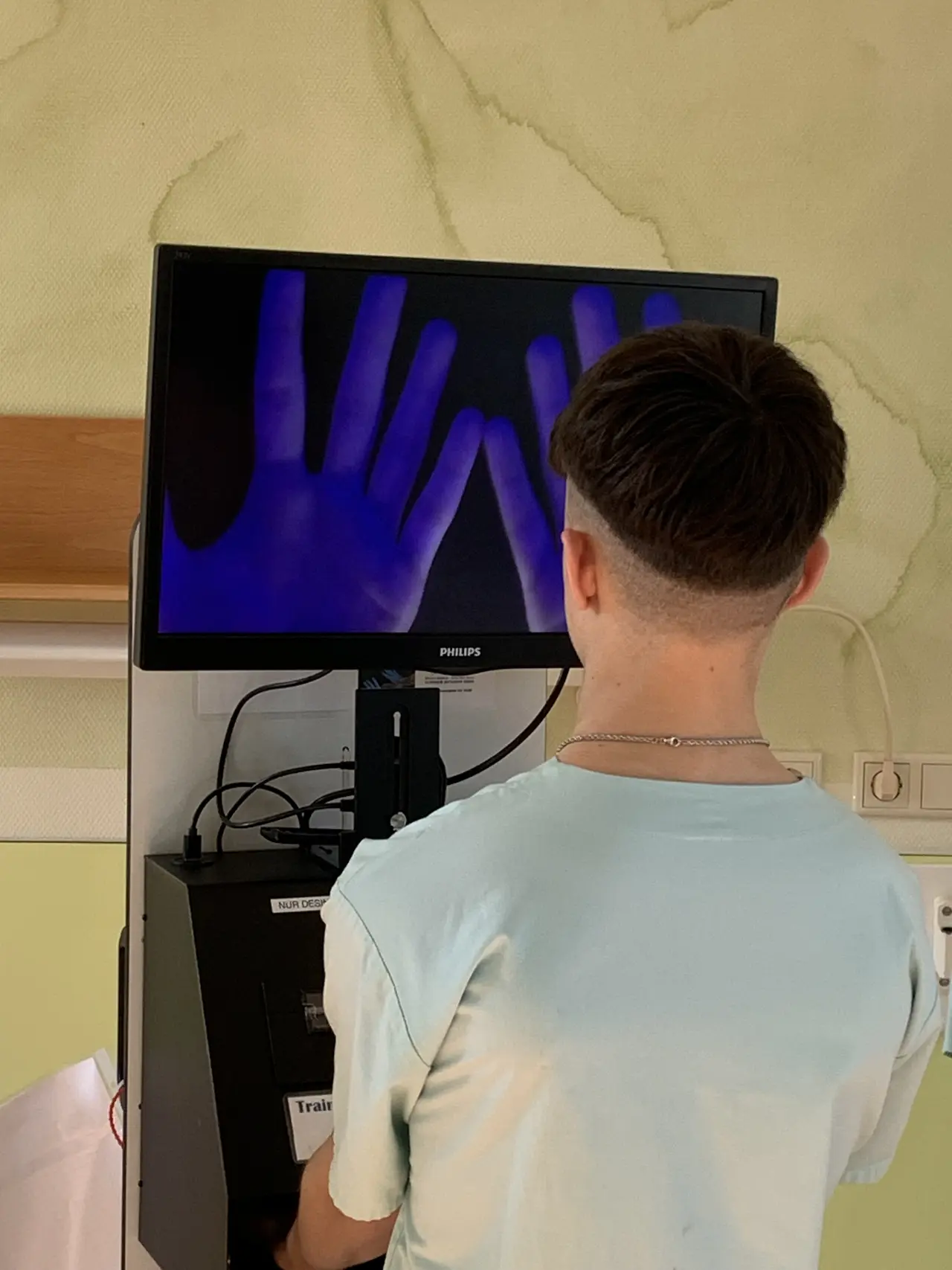 Junge steht vor einem Bildscanner und durchleuchtet seine eigenen Hände