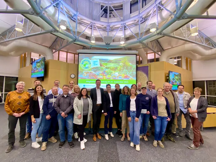 Eine größere Gruppe von Personen steht in einem Besprechungssaal